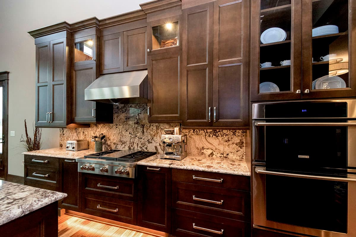 Dark wood kitchen cabinetry with granite countertops, stainless steel range, and double wall oven.
