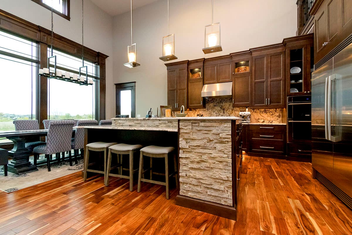 Kitchen with island, dark wood cabinetry, stainless steel appliances, and large windows overlooking dining area.