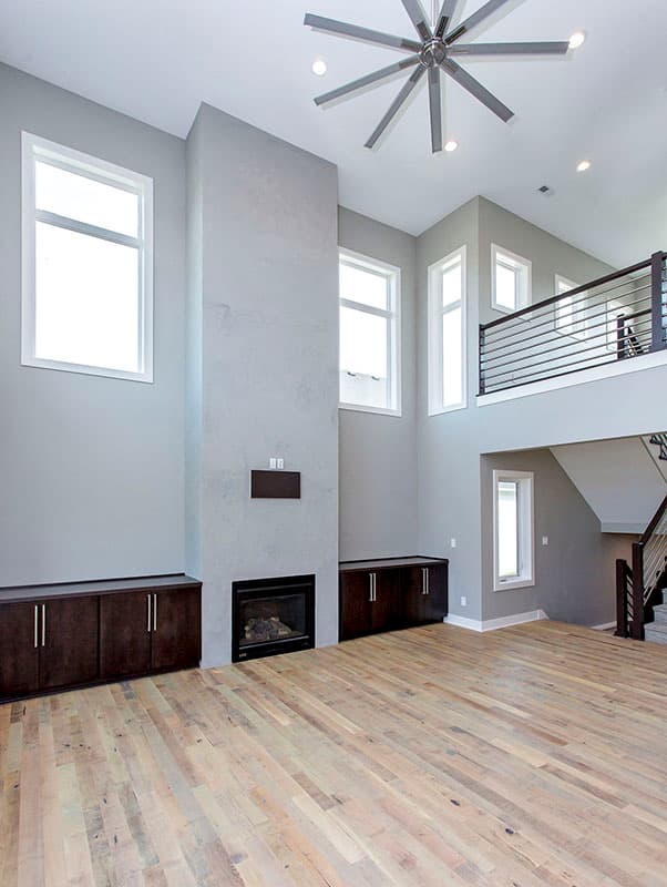 Great room with fireplace, floor-to-ceiling windows, vaulted ceiling with fan, and open loft.