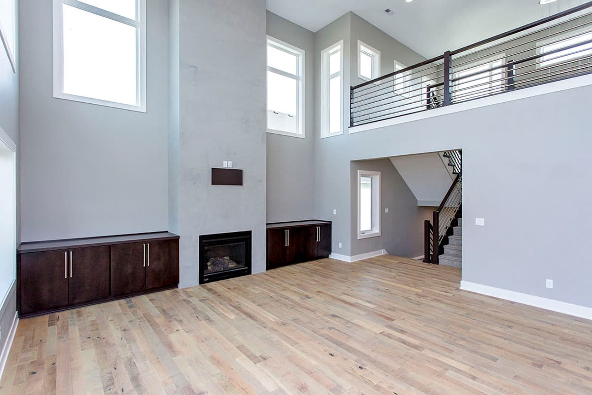 Great room interior with fireplace, built-in cabinets, open loft with railing, and a two-story window feature.