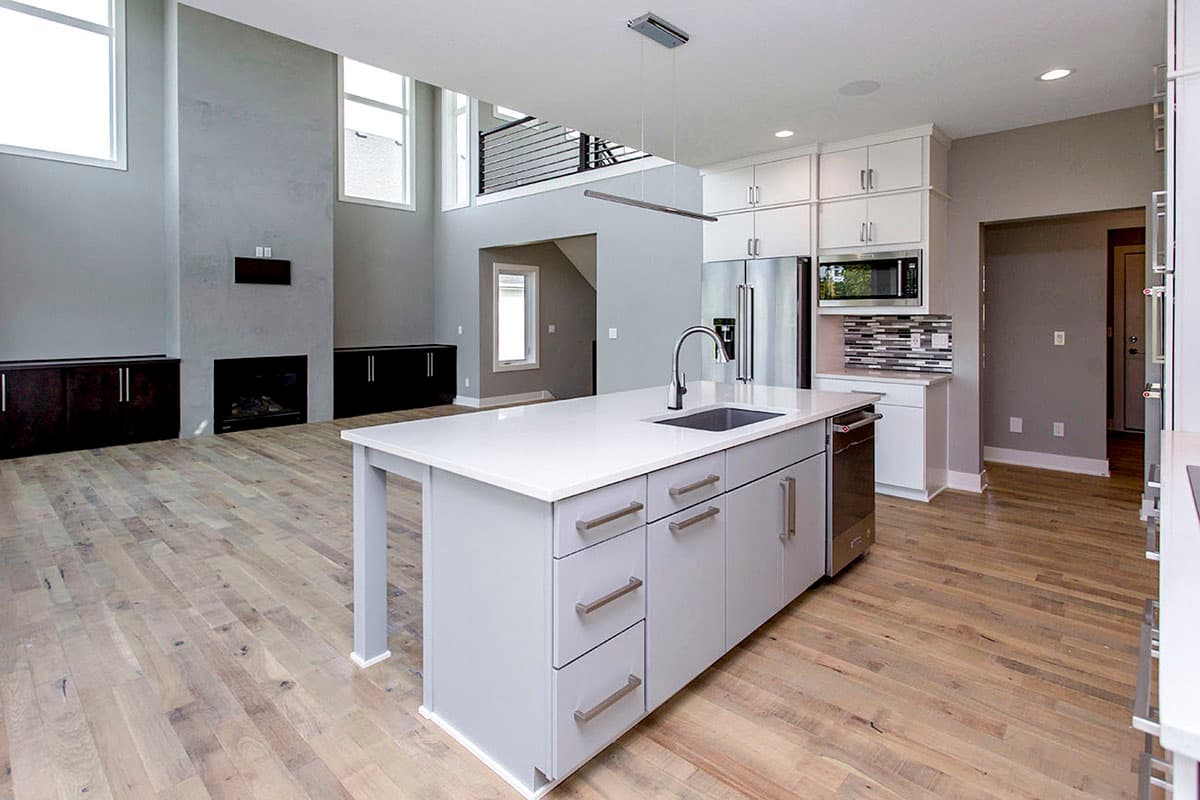 Interior view of open-concept living space with kitchen island, fireplace, and vaulted ceiling.