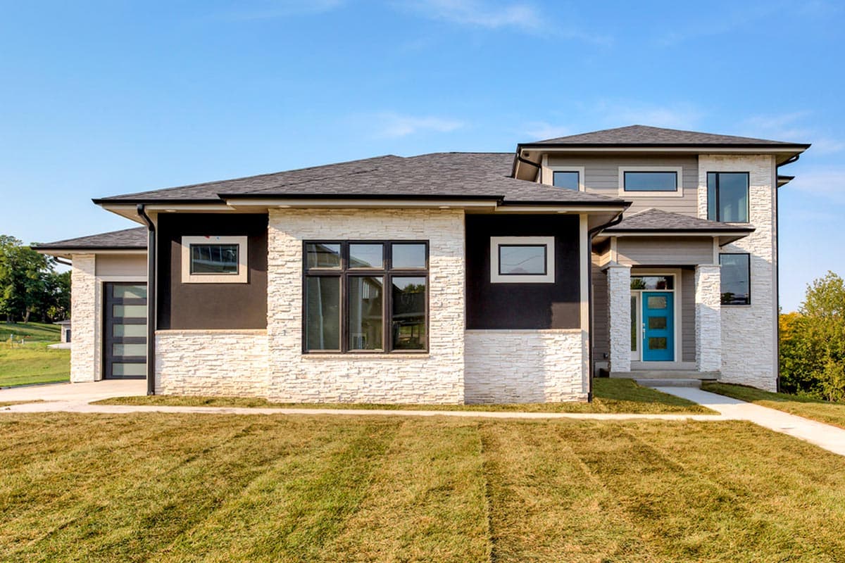 House plan exterior with stone veneer, flat roof, and two stories. Features include a garage, entry porch, and varying window styles.
