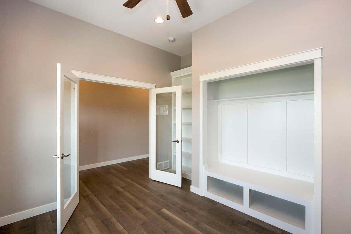 Interior view of a room with glass-paneled doors, built-in shelving, and a bench with cubbies.