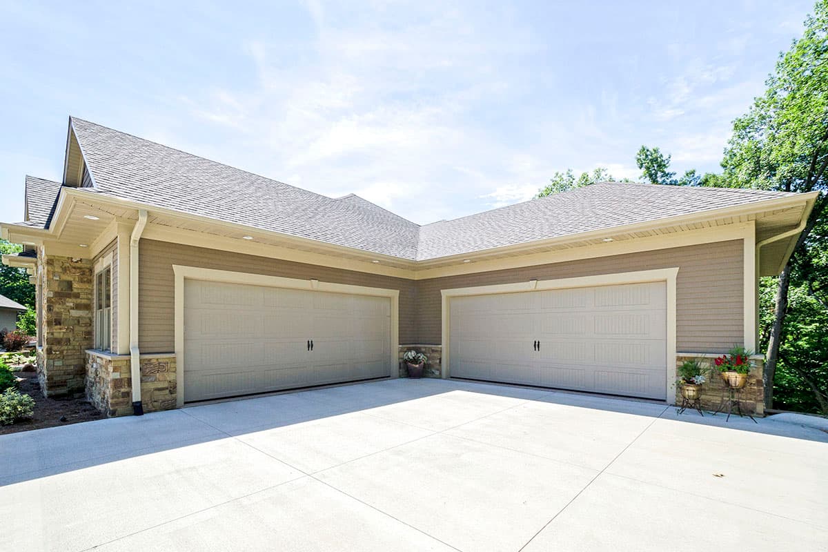 House plan exterior featuring a three-car garage with stone accents and layered gable rooflines.