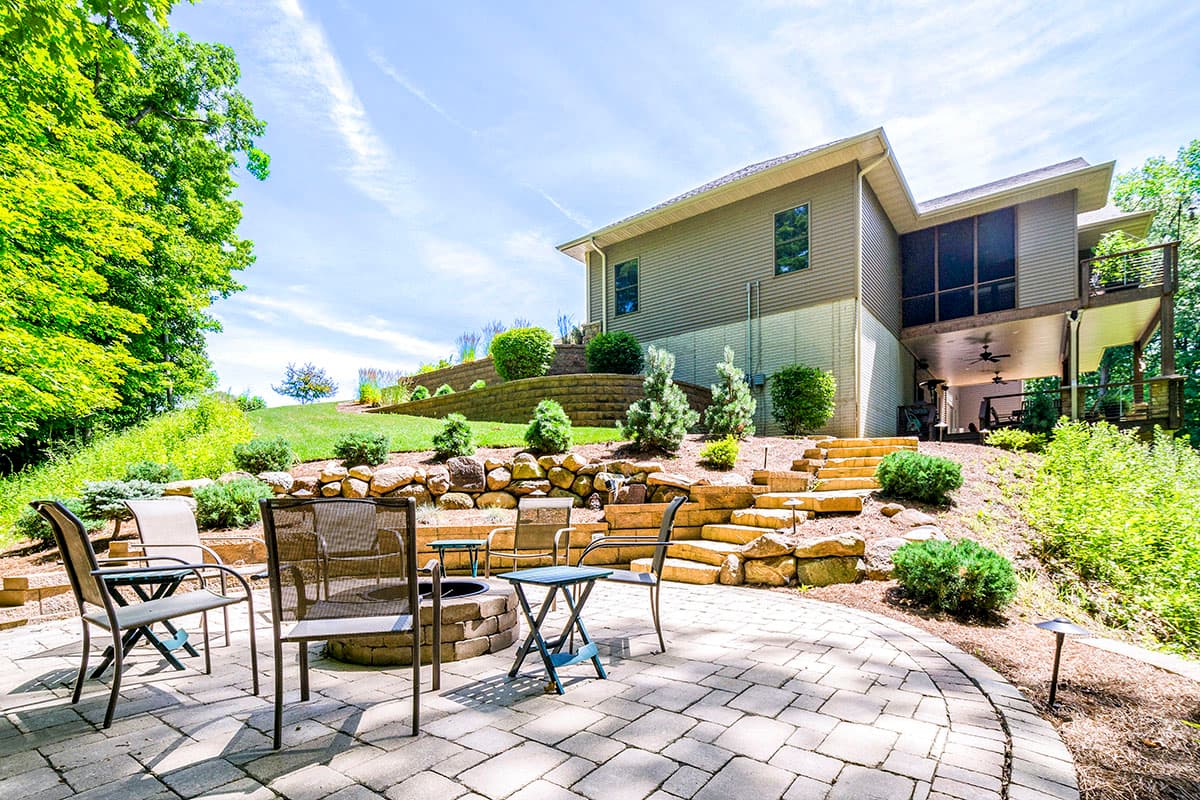 House plan exterior view of a multi-level home with a screened-in porch, deck, and terraced landscaping.