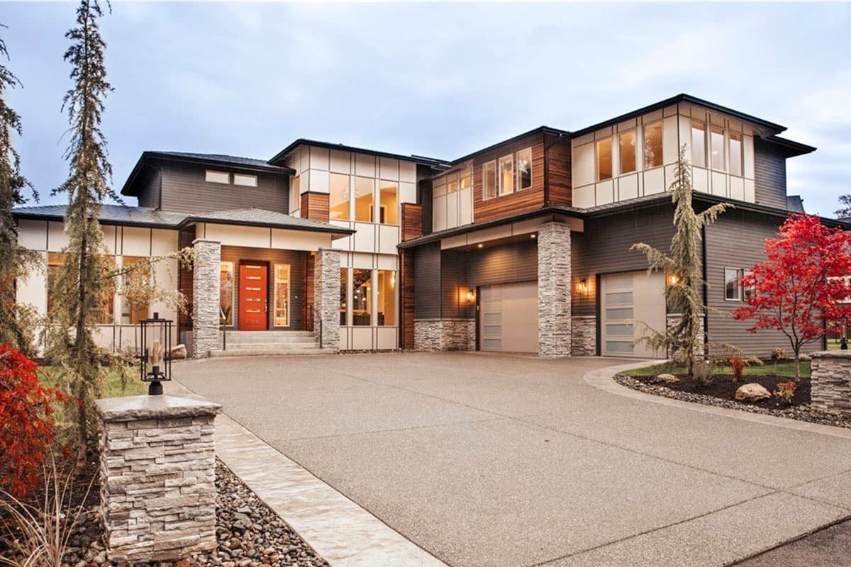 House plan exterior. Two-story modern house with a mix of siding and stone, accented by a covered entry and a two-car garage.