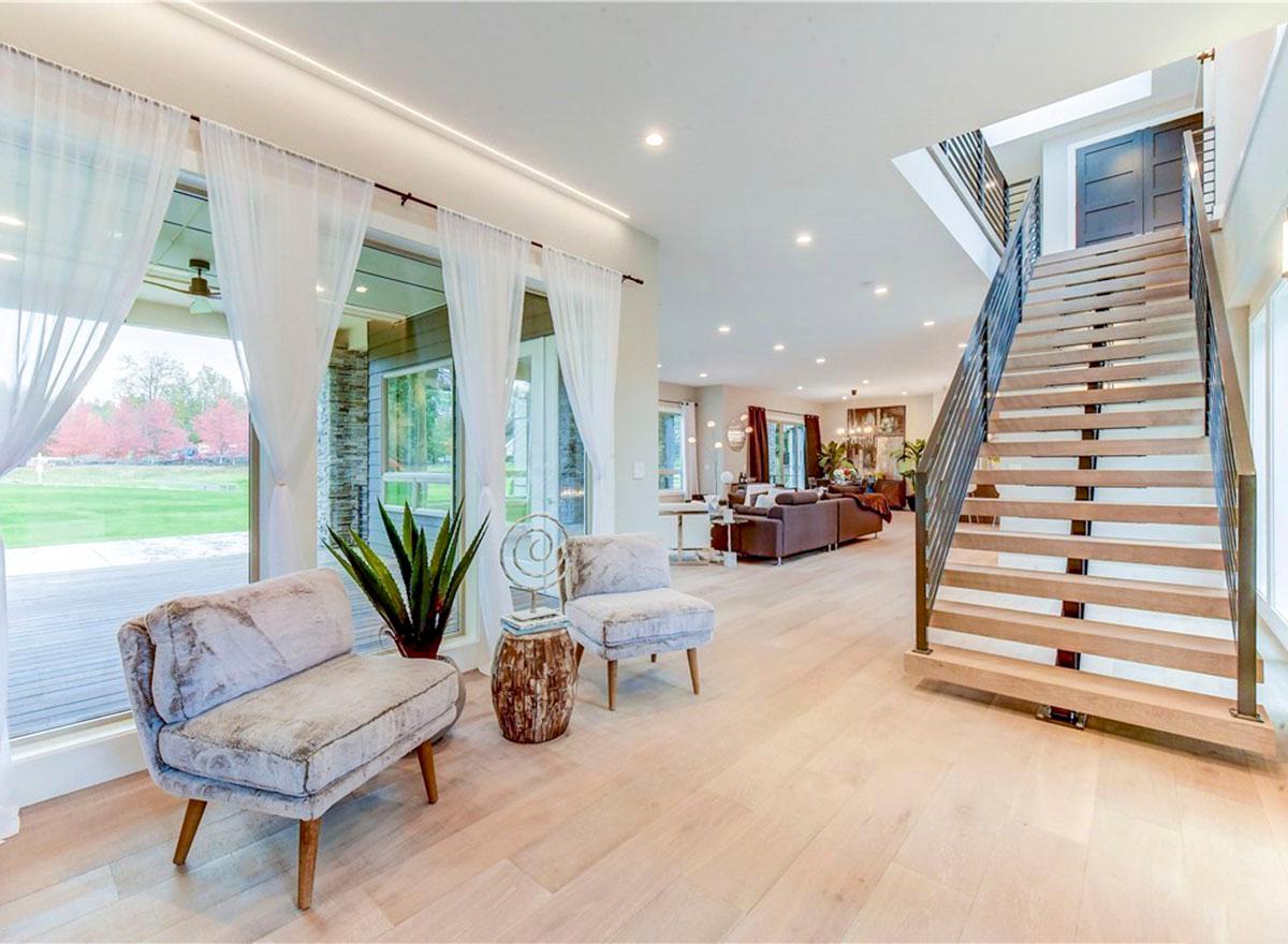 Interior view of a house with a floating staircase, large windows, and an open-concept living area.