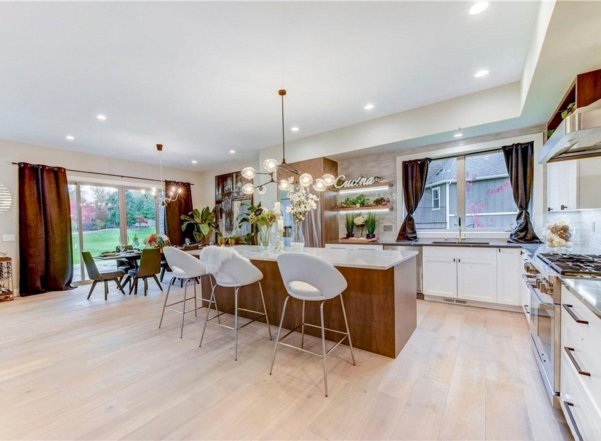 Open concept kitchen with island, dining area, large windows, and sliding glass doors to backyard.