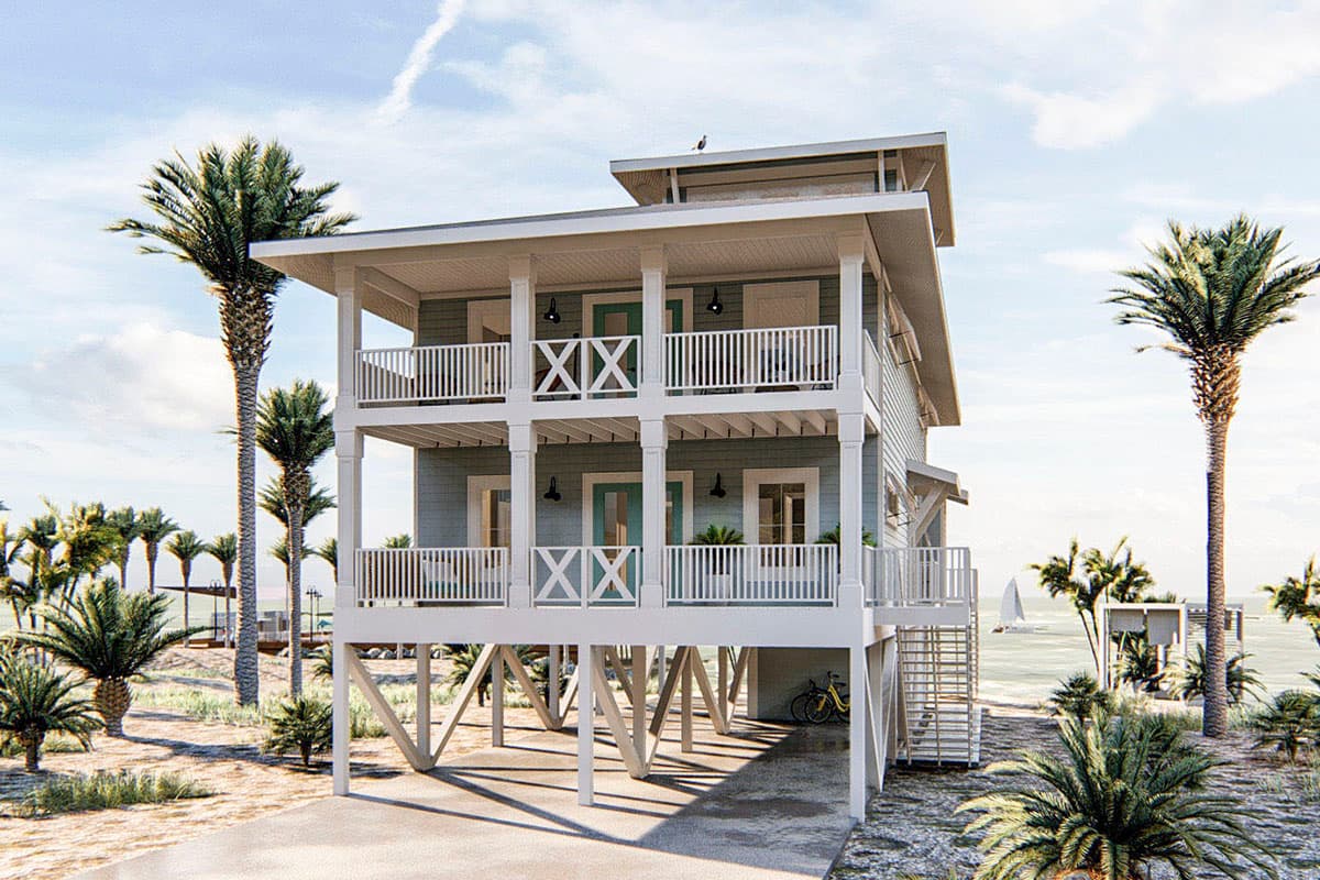 Two-story beach house exterior with a wrap-around balcony, a raised foundation, and a gable roof with a cupola.
