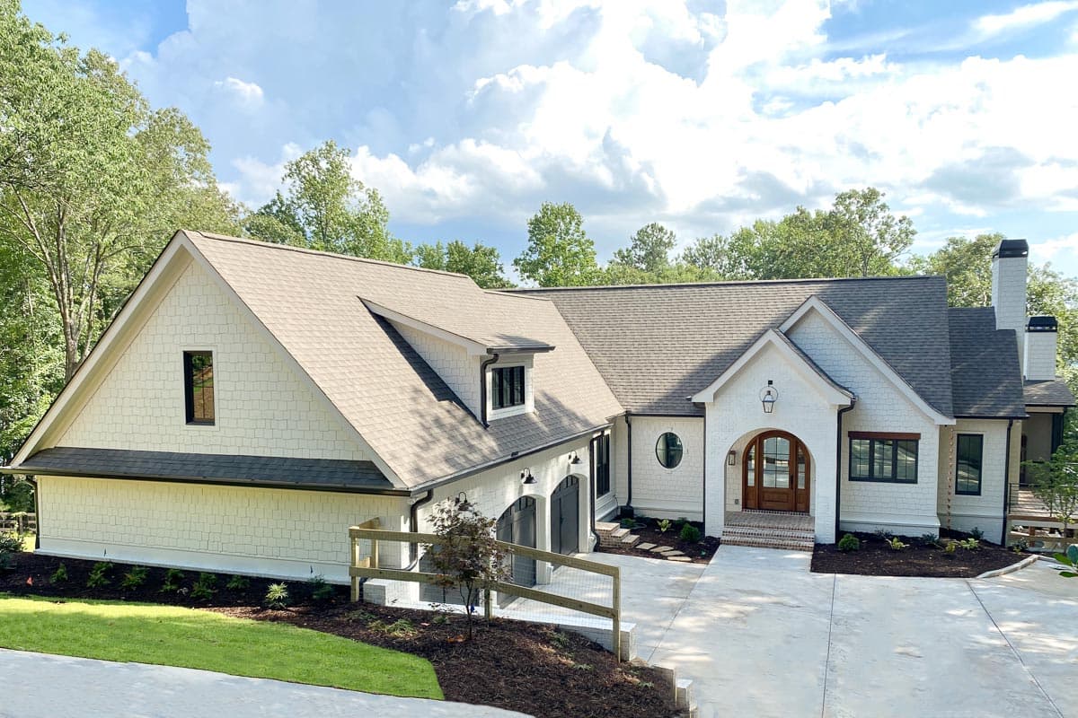 House plan exterior: Modern Farmhouse style, one story, with arched entry, prominent gables, dormer window, and side-entry garage.