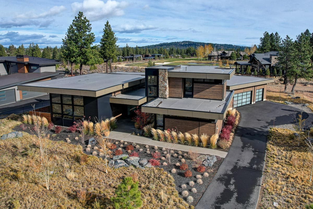 Modern house plan exterior featuring flat rooflines, large windows, wood siding, and a three-car garage.