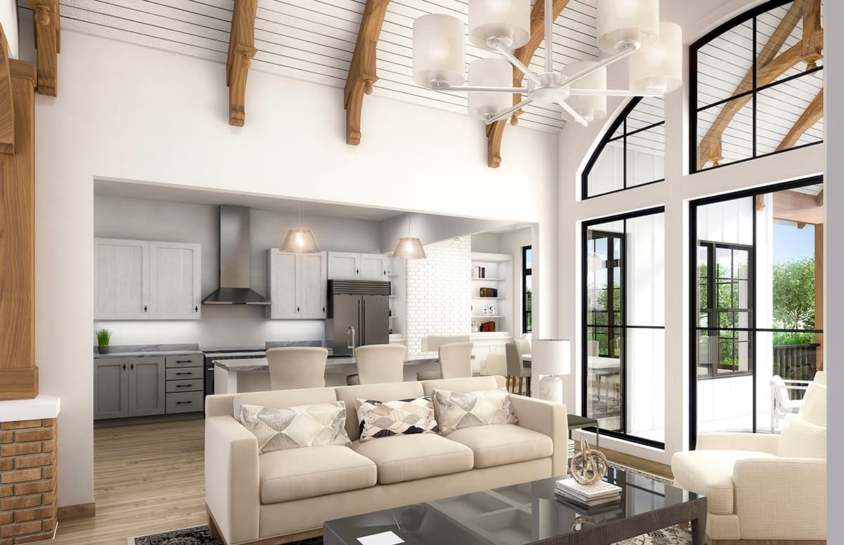 Open concept living area with vaulted ceilings, exposed beams, large windows, and view into a modern kitchen.