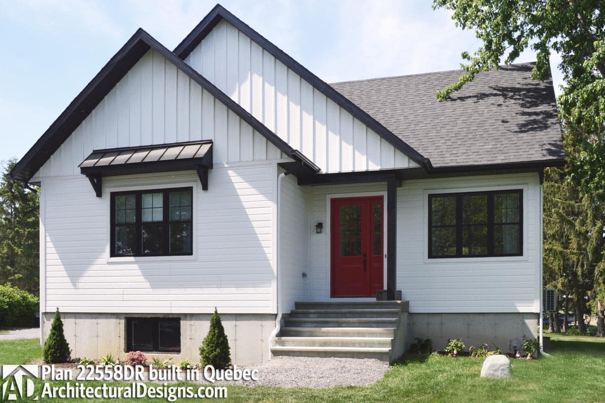 House plan exterior: Modern farmhouse style, two stories, white board and batten siding, red double entry door, dark gables.