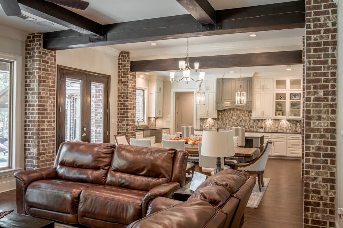 Spacious, open-plan living and kitchen area with leather sofa, dining table, and exposed brick accents, creating a warm and inviting atmosphere.