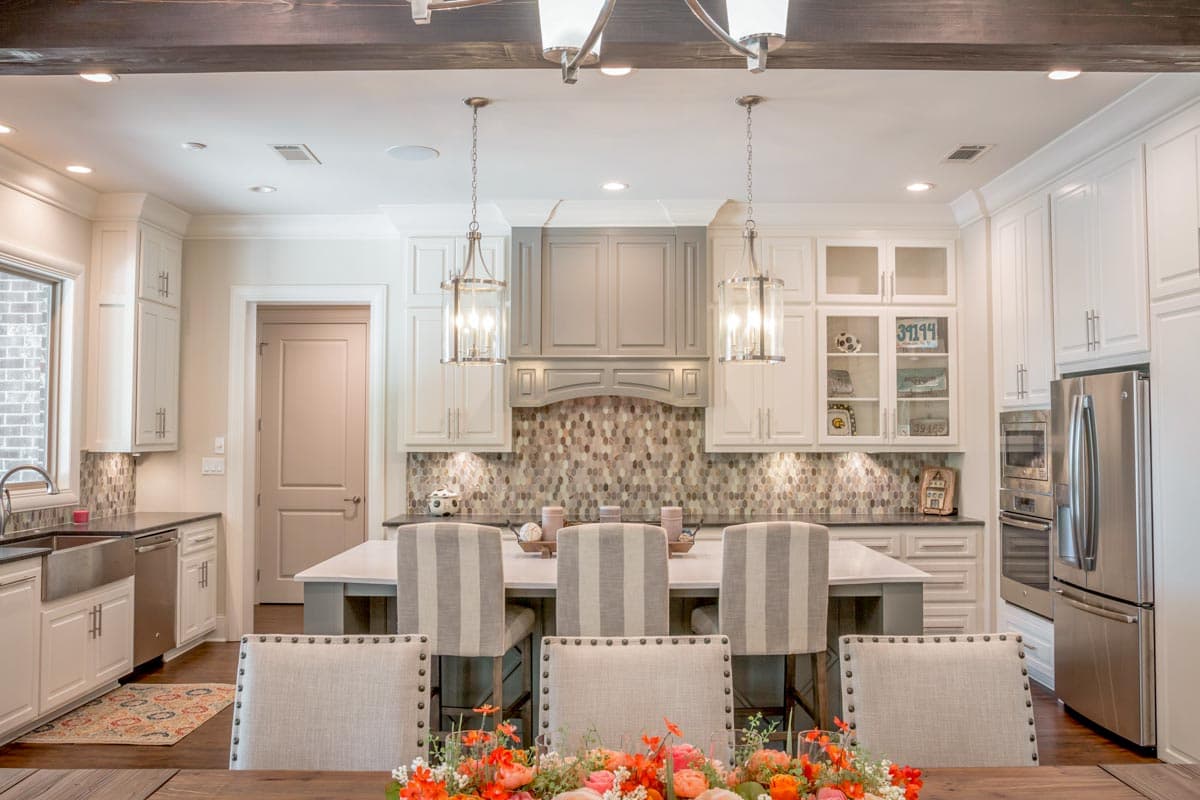 A modern kitchen with a large island and seating. Overhead, two pendant lights illuminate the space. Soft colors create a welcoming ambiance.
