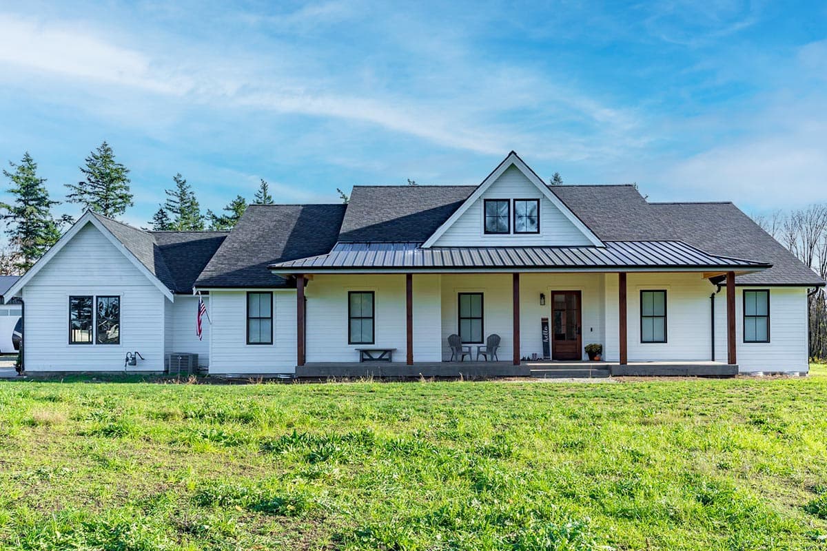 House plan exterior. Modern farmhouse style. One-story home with front porch, gable over entry, and shed roof over porch area.