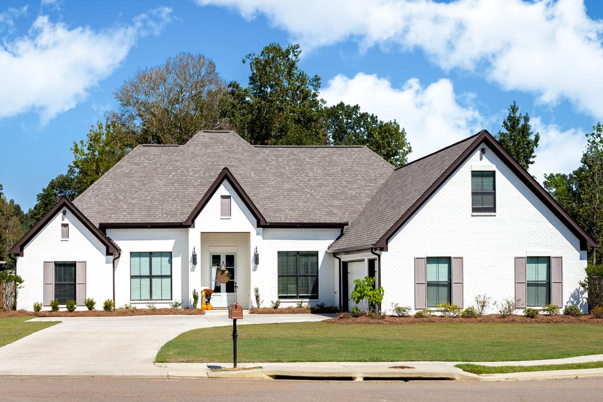 House plan exterior of a one-story Modern Farmhouse with a white brick facade, prominent gables, and a covered entry.