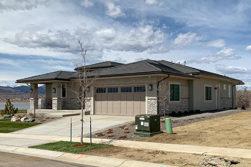 House plan exterior: Modern single-story with a covered entry porch, stone accents, and a three-car garage.