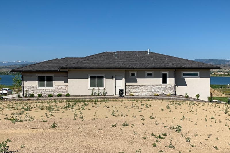 House plan exterior, one story, stucco finish with stone wainscoting, hipped roof, and varied window sizes.