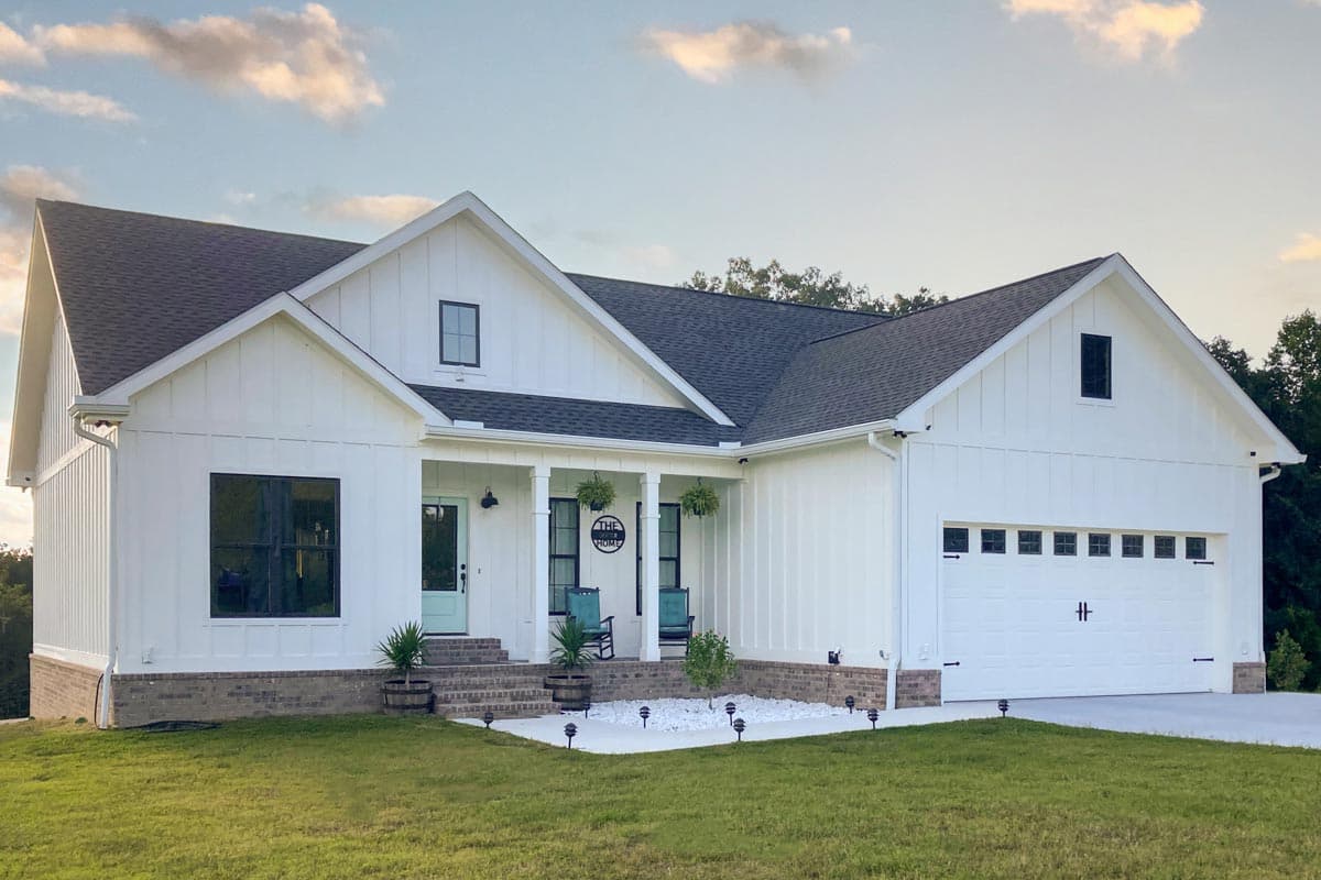 Modern Farmhouse style house plan exterior with white board and batten siding, gabled rooflines, covered porch, and attached two-car garage.