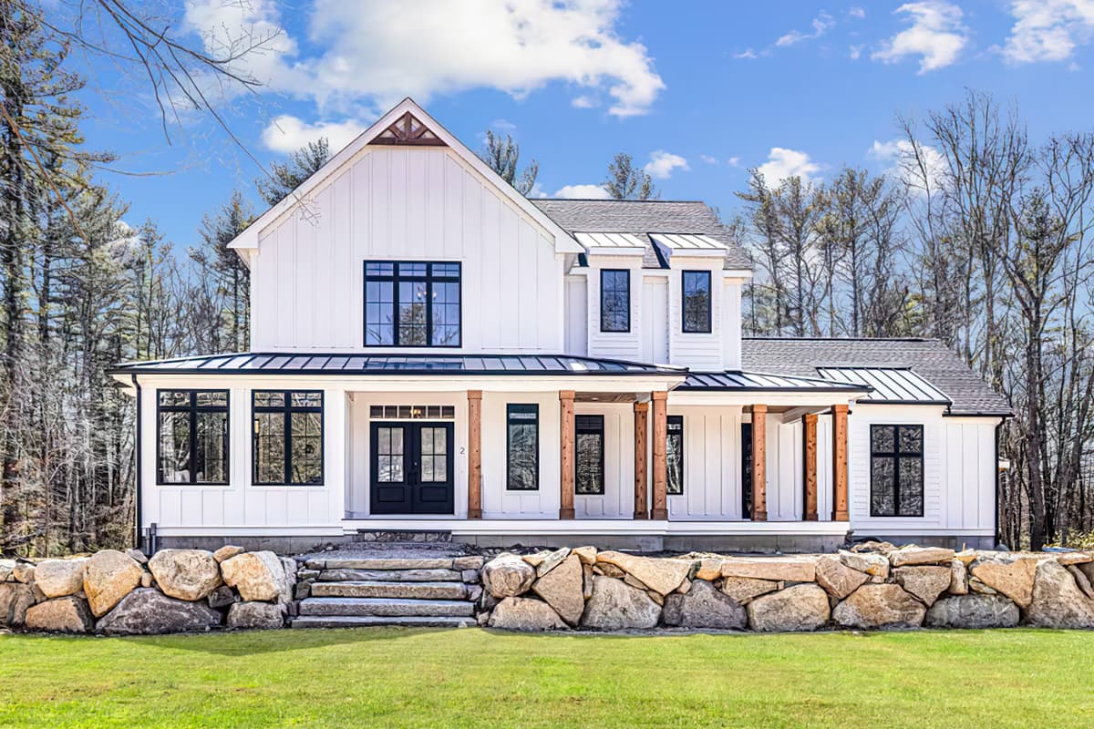 House plan exterior. Two-story Modern Farmhouse with a gabled roof, covered porch with wood columns, and multiple black-framed windows.