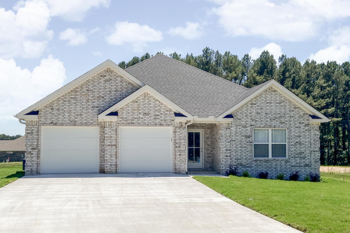 Exterior house plan with white brick facade, two-car garage, gabled dormers, and gray roof.