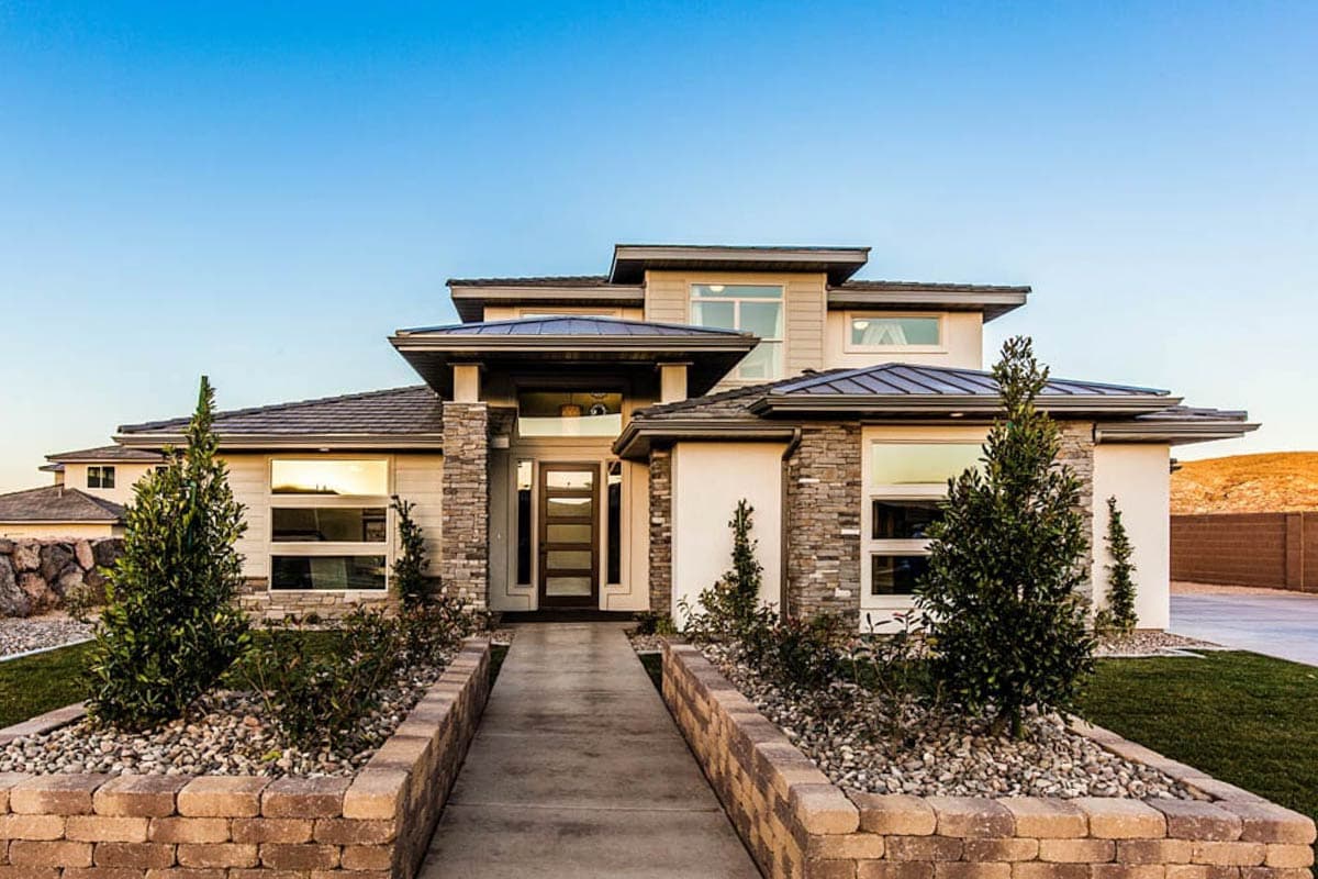 Modern two-story house plan exterior with stone accents, multiple rooflines, and a covered entry with glass door.
