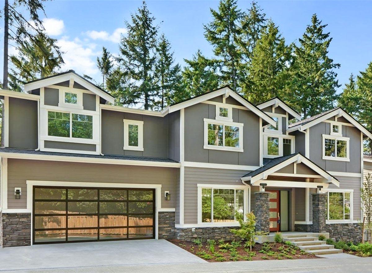 House plan exterior. Two-story home with Craftsman influence. Features include gables, dormers, and a glass-paneled garage door.