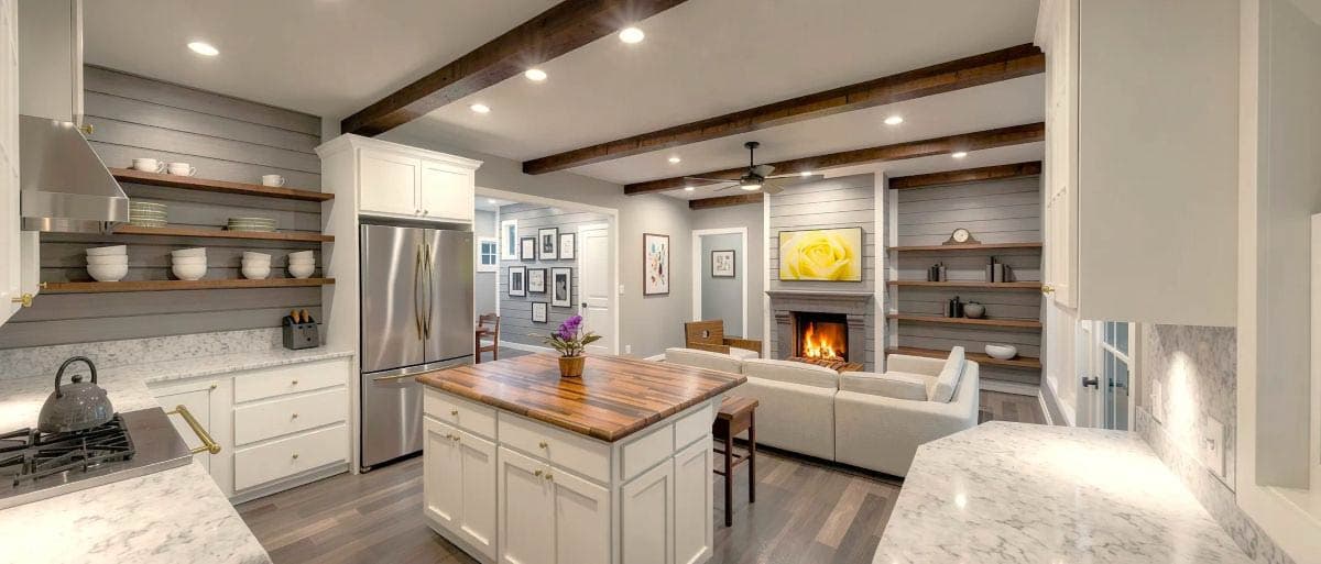 Interior rendering of an open concept kitchen and great room with island, fireplace, and wood beams.
