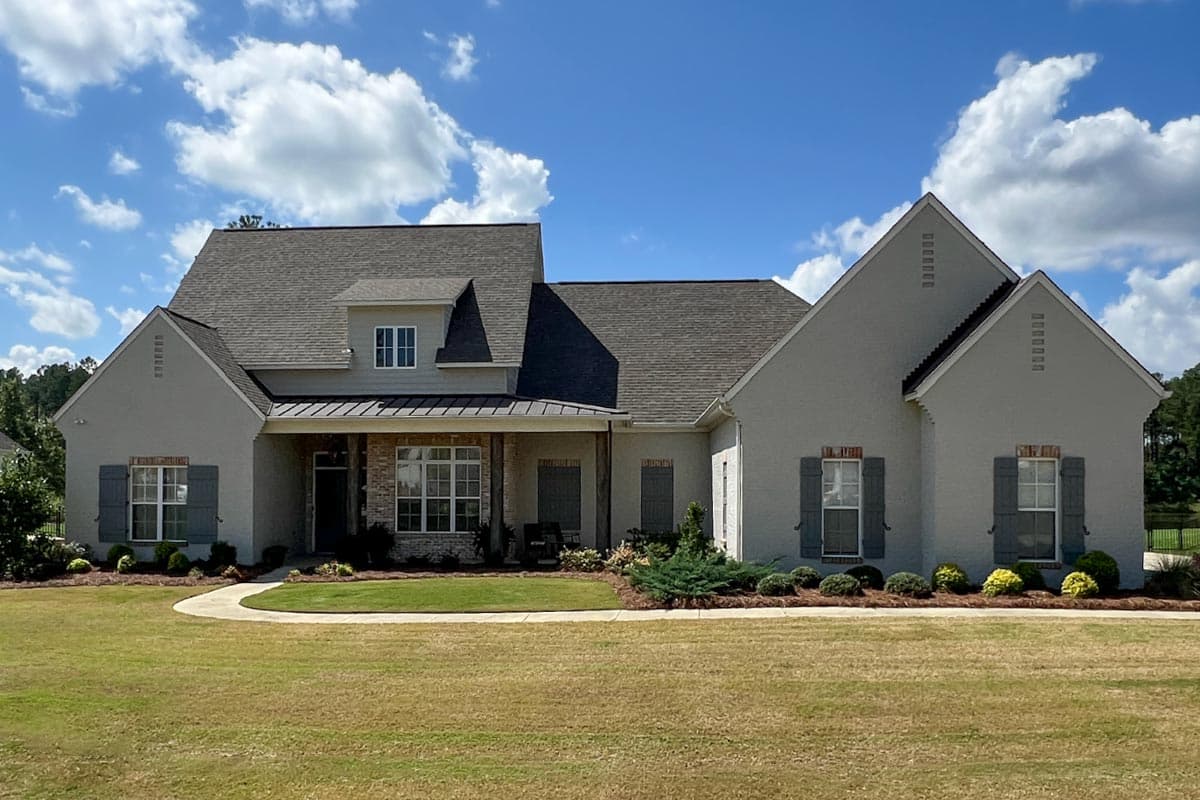 House plan exterior: one-and-a-half stories, multiple gables, dormer, covered entryway with stone accents, and gray shutters.