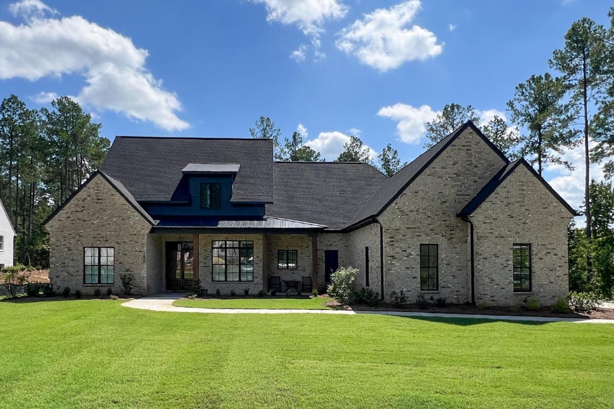 House plan exterior, one story, brick construction, covered porch, prominent gables, and dark metal dormer.