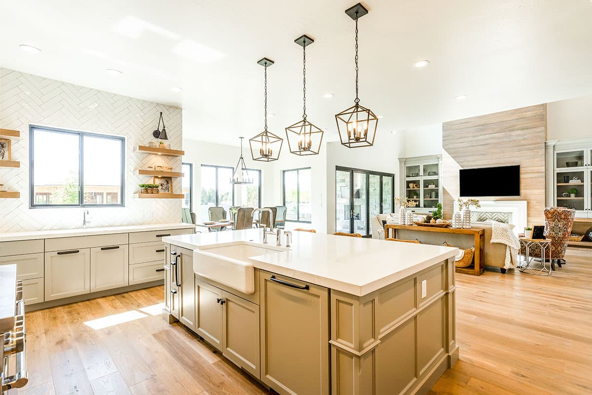 Open-concept kitchen and living area with island, fireplace, built-in cabinetry, and large windows.