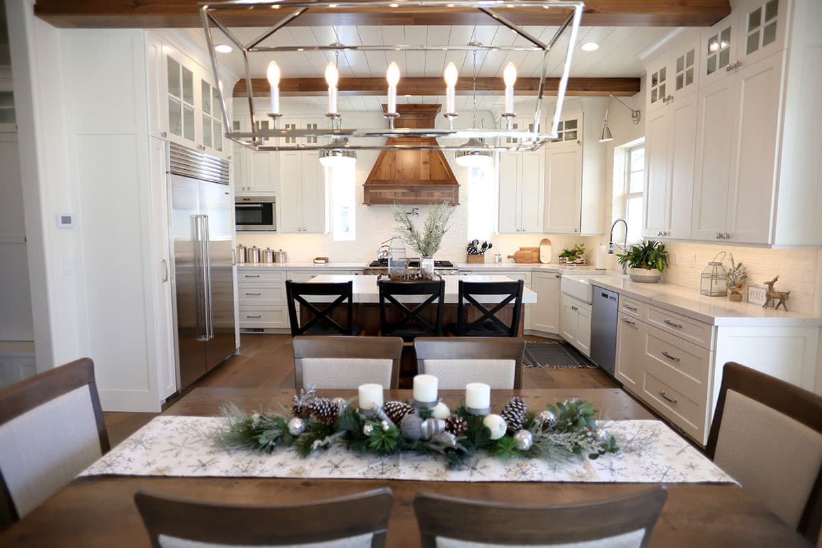 Contemporary kitchen with white cabinets, large island, farmhouse sink, and exposed wood beams.
