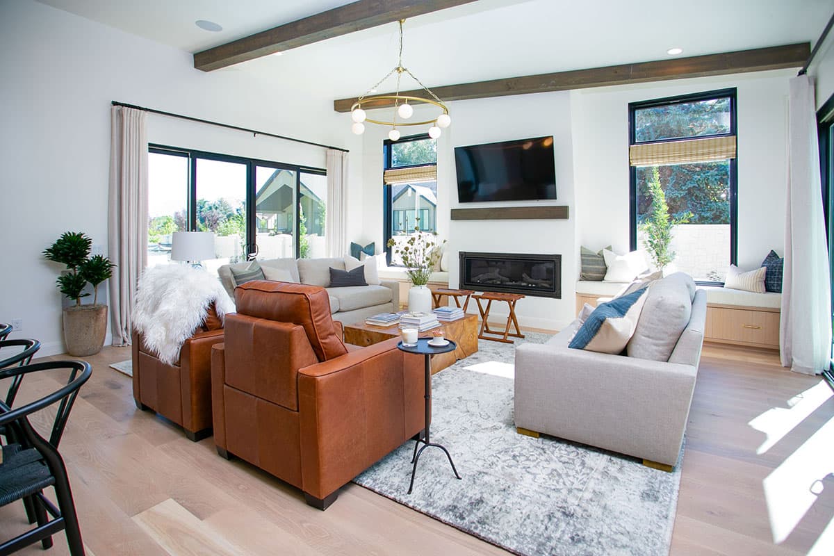 Interior view of living room with fireplace, seating area, exposed beams, and large windows.