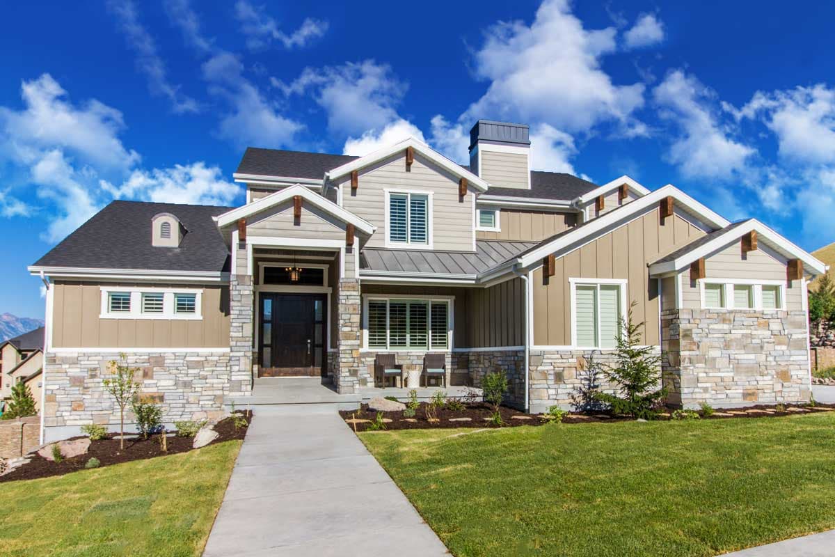 House plan exterior featuring Craftsman style, two stories, stone accents, gables, and a prominent entryway. Dark roof and chimney visible.