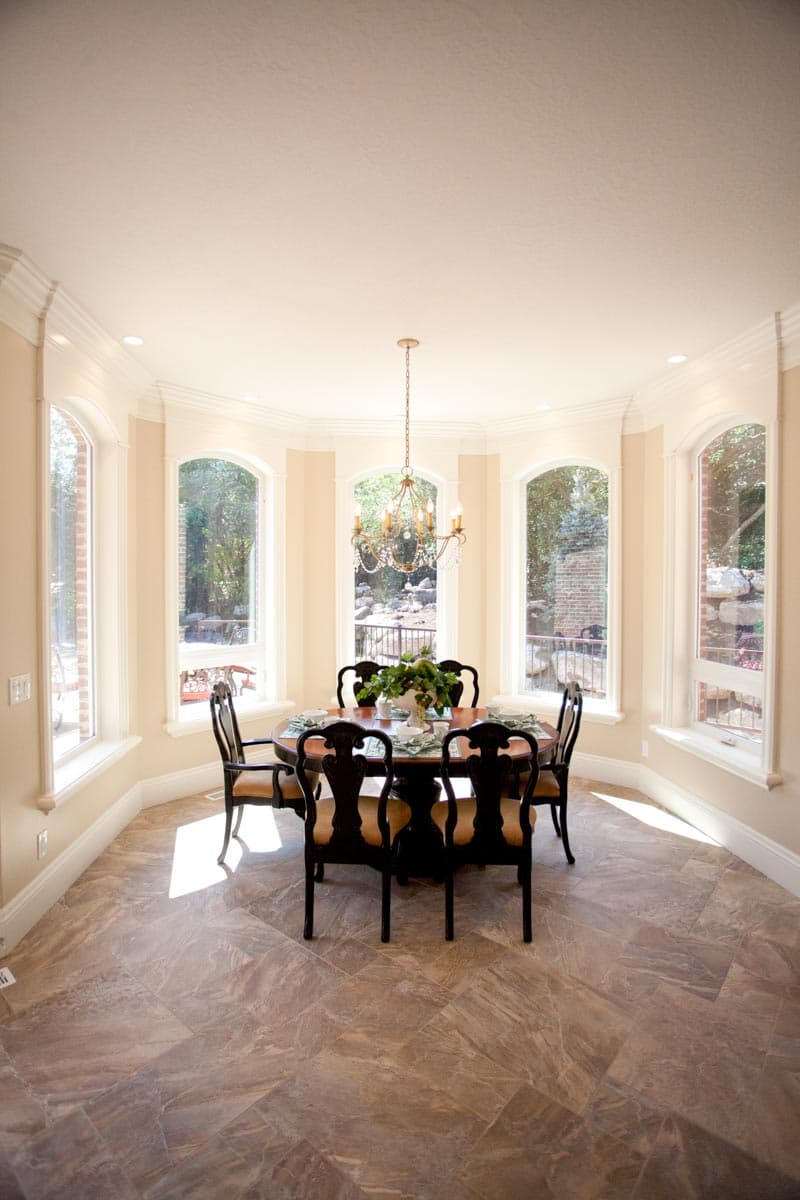 Dining room with bay windows, chandelier, and round table set for six.