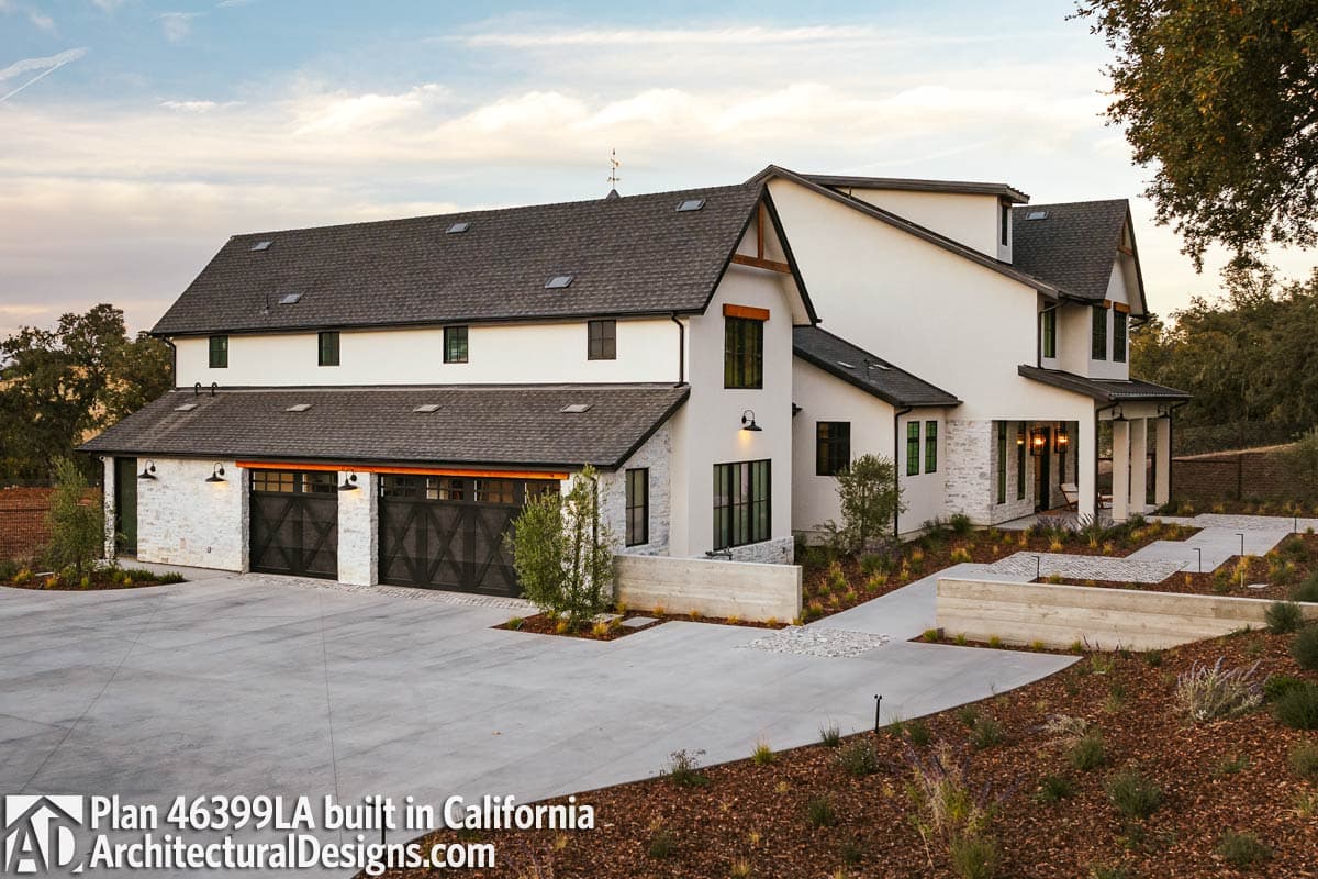 Modern Farmhouse house plan exterior with a dark roof, white stucco, stone base, and triple garage doors.