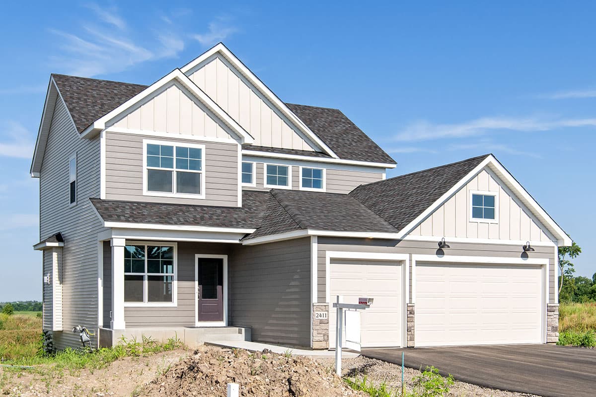 Two-story house plan exterior with gabled dormers, vinyl siding, and a two-car garage.