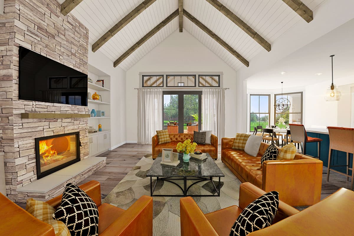 Great room with stone fireplace, vaulted beamed ceiling, seating area and adjacent dining and kitchen.