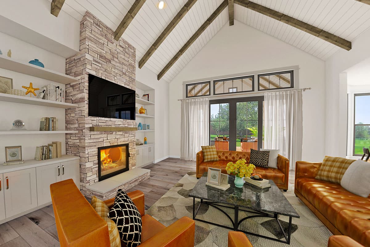 Great room interior with vaulted ceiling, wood beams, stone fireplace, built-in shelves and large glass doors.