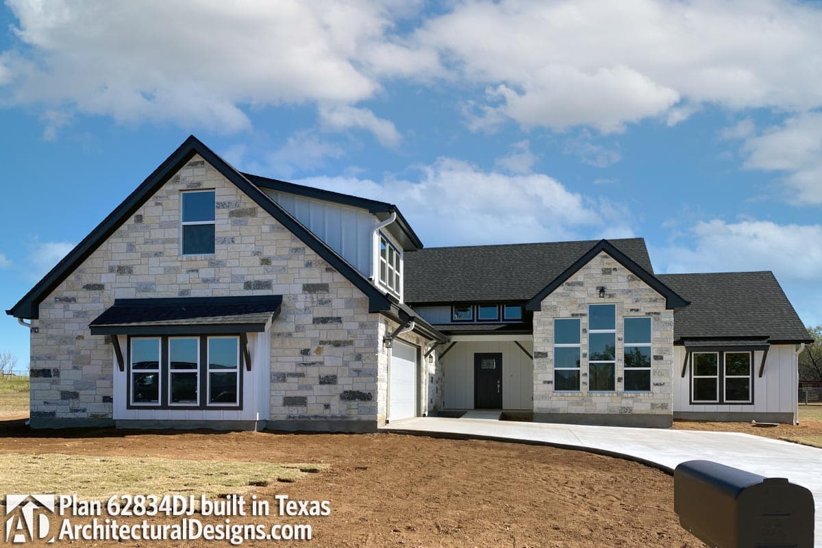 House plan exterior featuring stone accents, board and batten siding, a prominent gable, and multiple large windows.