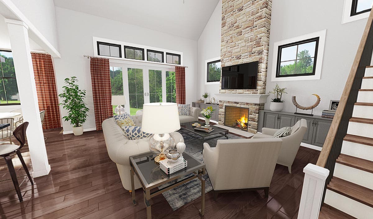 Great room with vaulted ceiling, stone fireplace, and wood floors. Staircase visible.