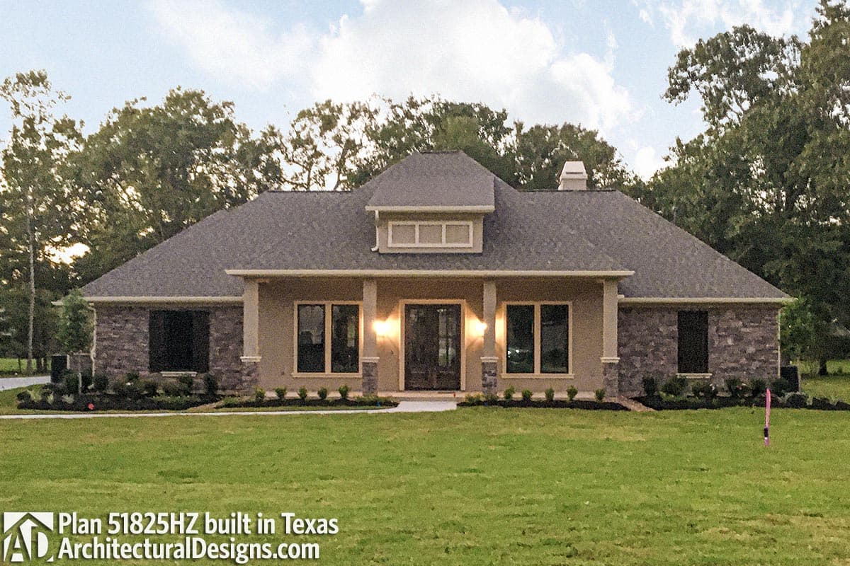 House plan exterior: one-story, hip roof, stone accents, dormer, covered entry with columns.