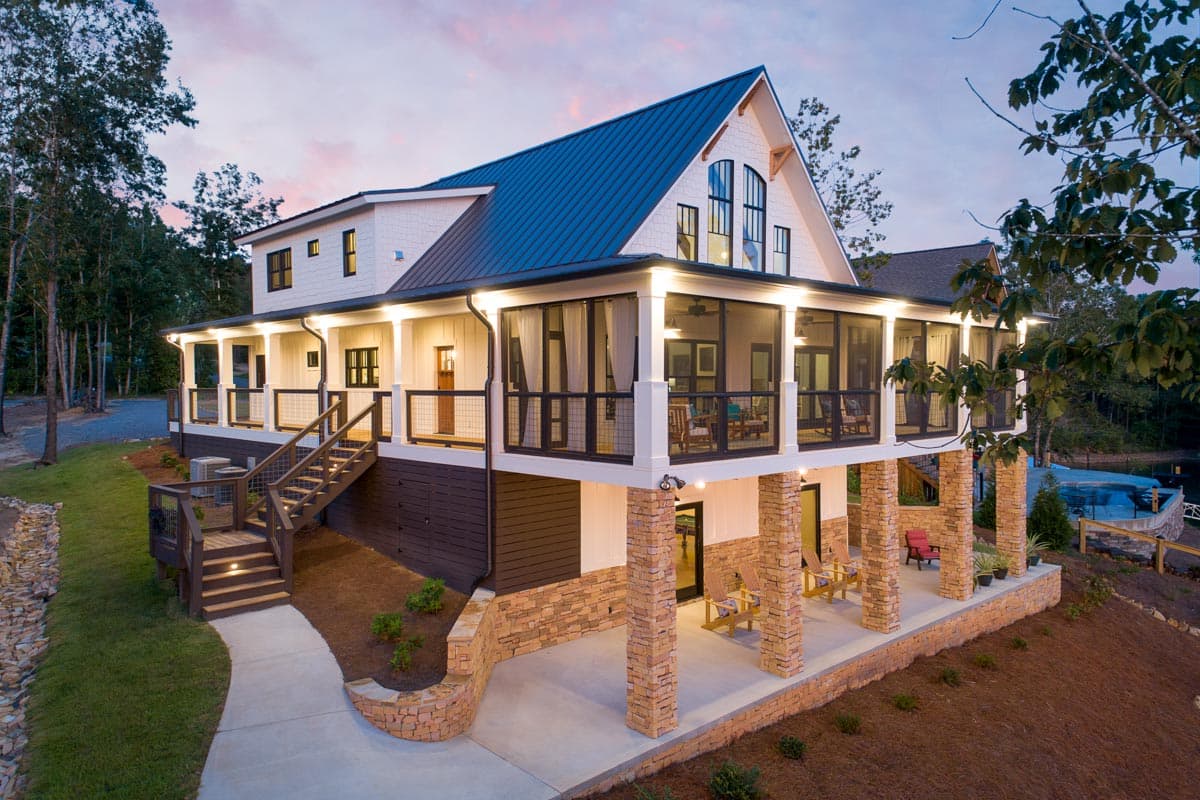 House plan exterior with Craftsman style. Features a covered porch, gabled roof, and stacked stone pillars. Two-story structure with a metal roof.