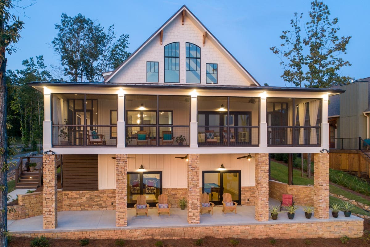 Modern Farmhouse house plan exterior with two levels of porches, stone foundation, and a prominent gable with arched windows.