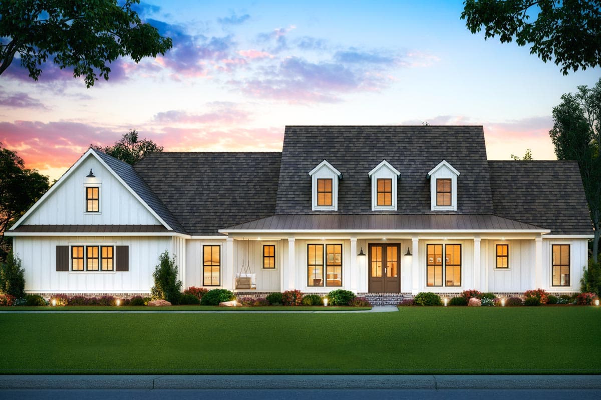 A large, modern farmhouse with white siding, dark trim, and a welcoming porch. The lawn is green, the sky a mix of blue and pink hues.