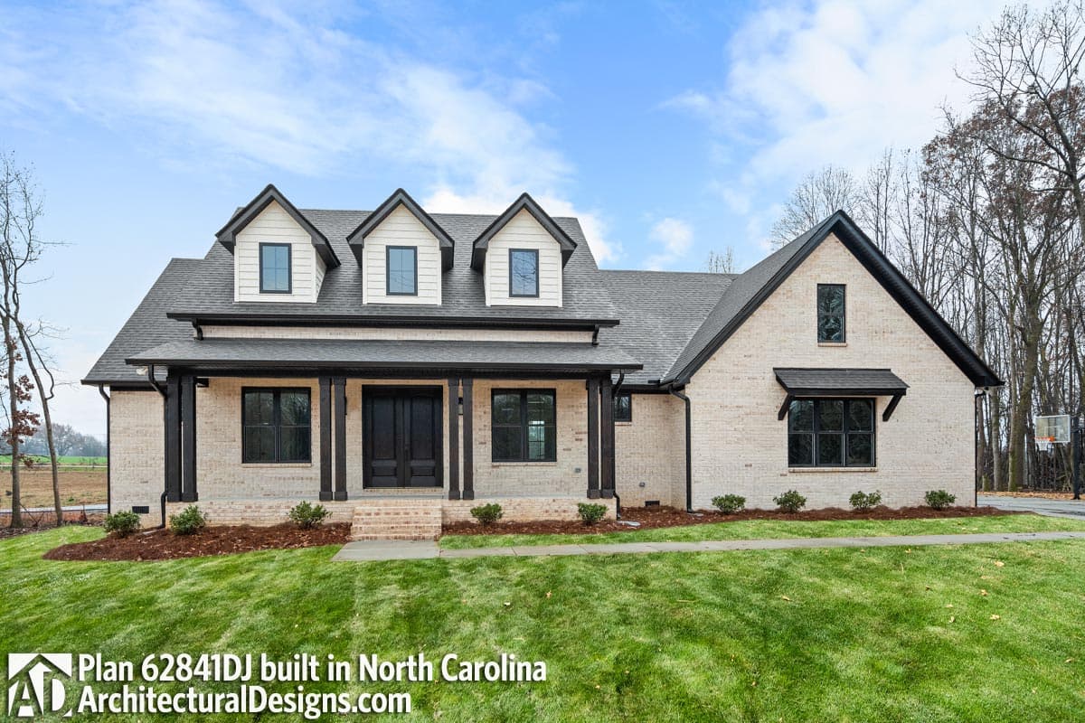 House plan exterior: two-story Modern Farmhouse with prominent front porch, gabled dormers, and white brick.