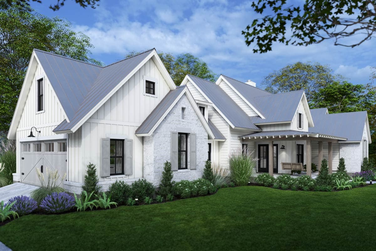 A modern farmhouse with white siding, stone accents, and a gray metal roof, set amidst a well-manicured lawn with lush landscaping.