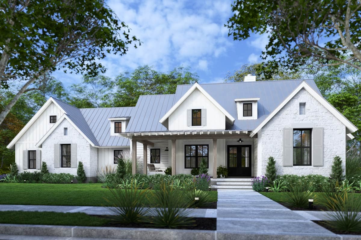 A white farmhouse with a light gray roof and shutters. A stone path leads up to the black double doors of the house.