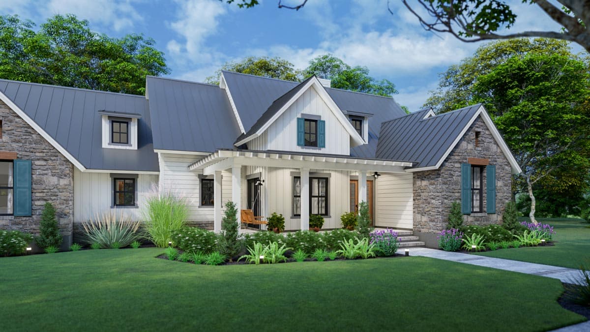 A farmhouse with a gray metal roof, stone and white siding, and a large porch. Lush green lawn and landscaping surround the home under a blue sky.